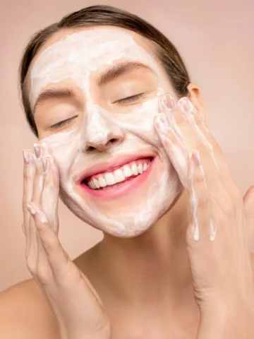 woman washing her face with foaming face wash to keep your skin happy