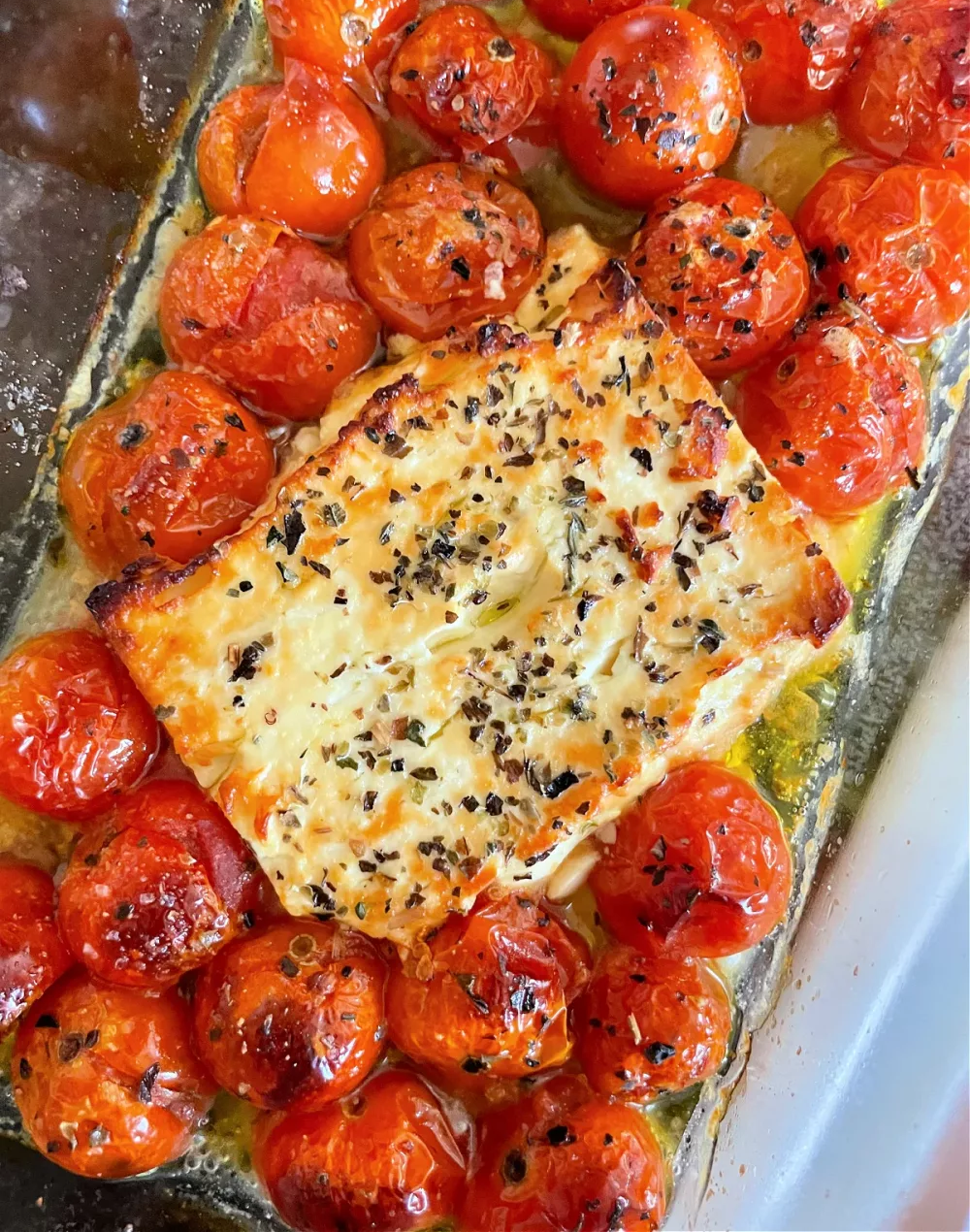 casserole dish filled with cherry tomatoes and brick of feta covered in italian seasonings