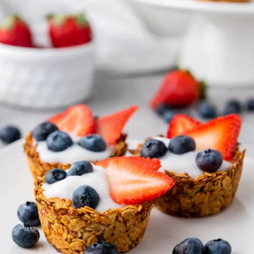 Granola Cups filled with yogurt and fresh berries on a white plate