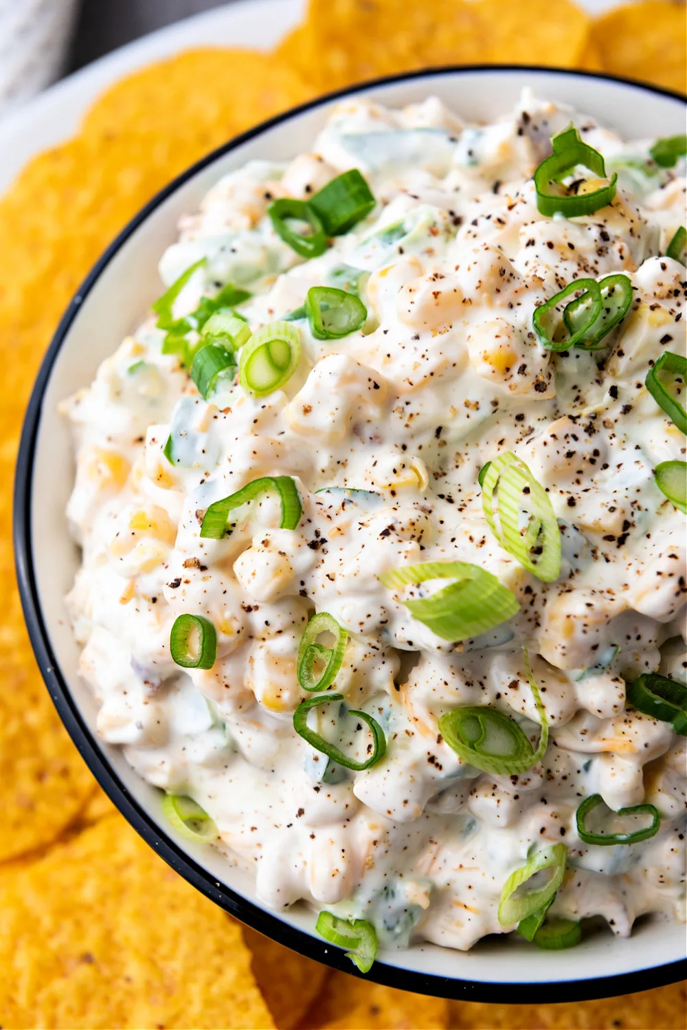 bowl full of creamy dip filled with corn, jalapenos and cheddar cheese