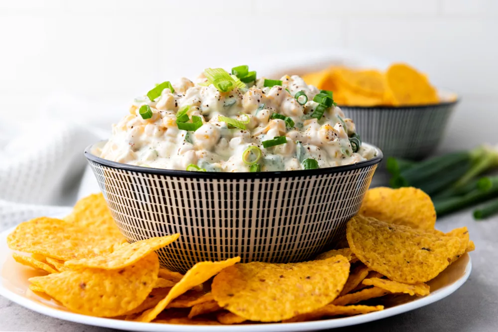 bowl full of creamy dip filled with corn, jalapenos and cheddar cheese