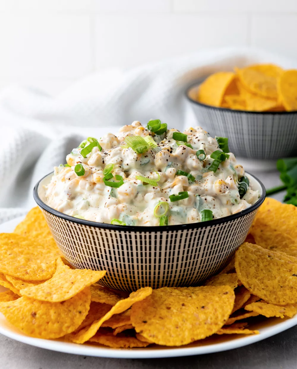 bowl full of creamy dip filled with corn, jalapenos and cheddar cheese