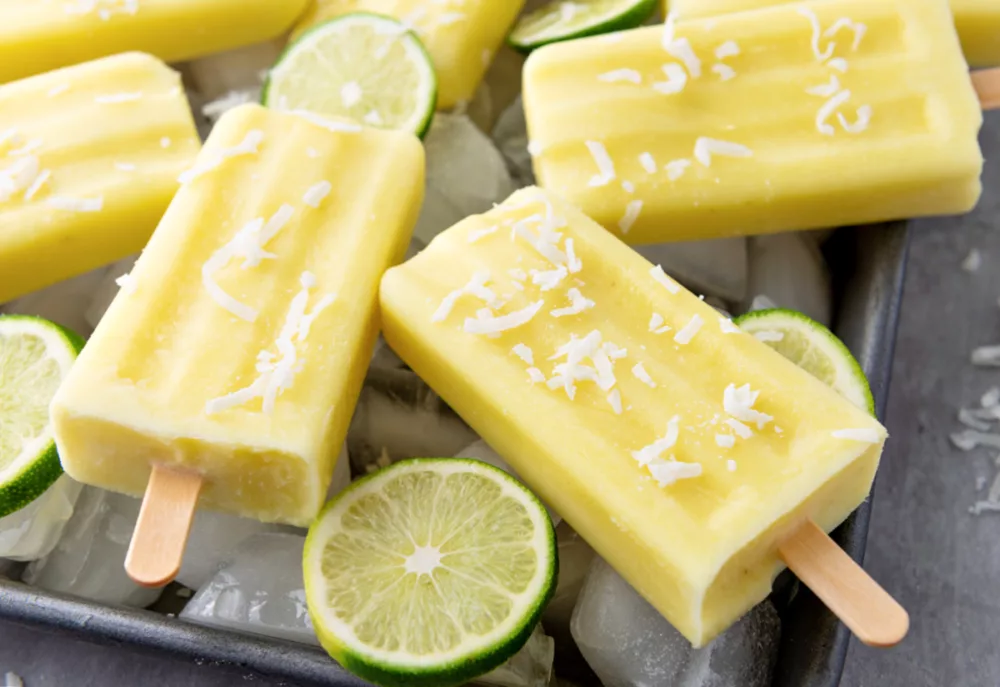 frozen fruit bars with shaved coconut on top and limes in the background