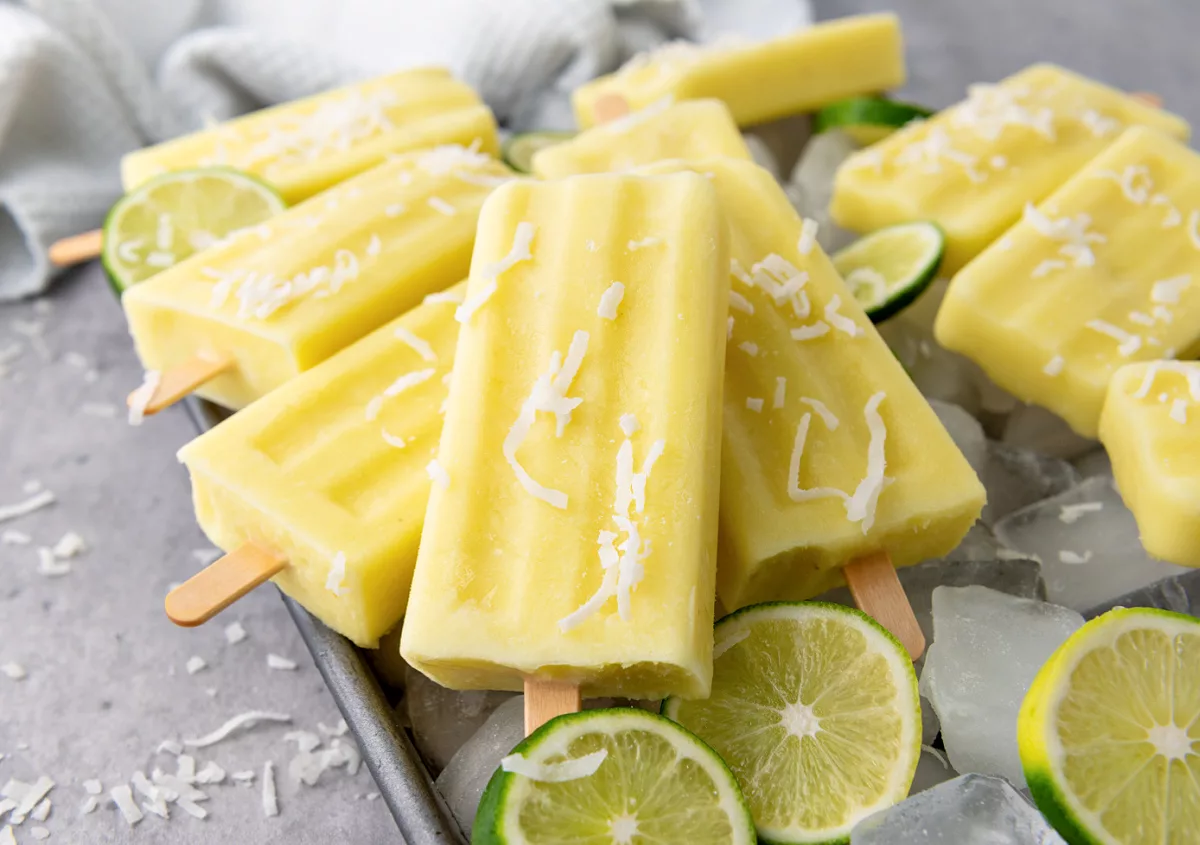 frozen fruit bars with shaved coconut on top and limes in the background