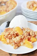 cobbler on a plate with slices of peaches and a big scoop of vanilla ice cream
