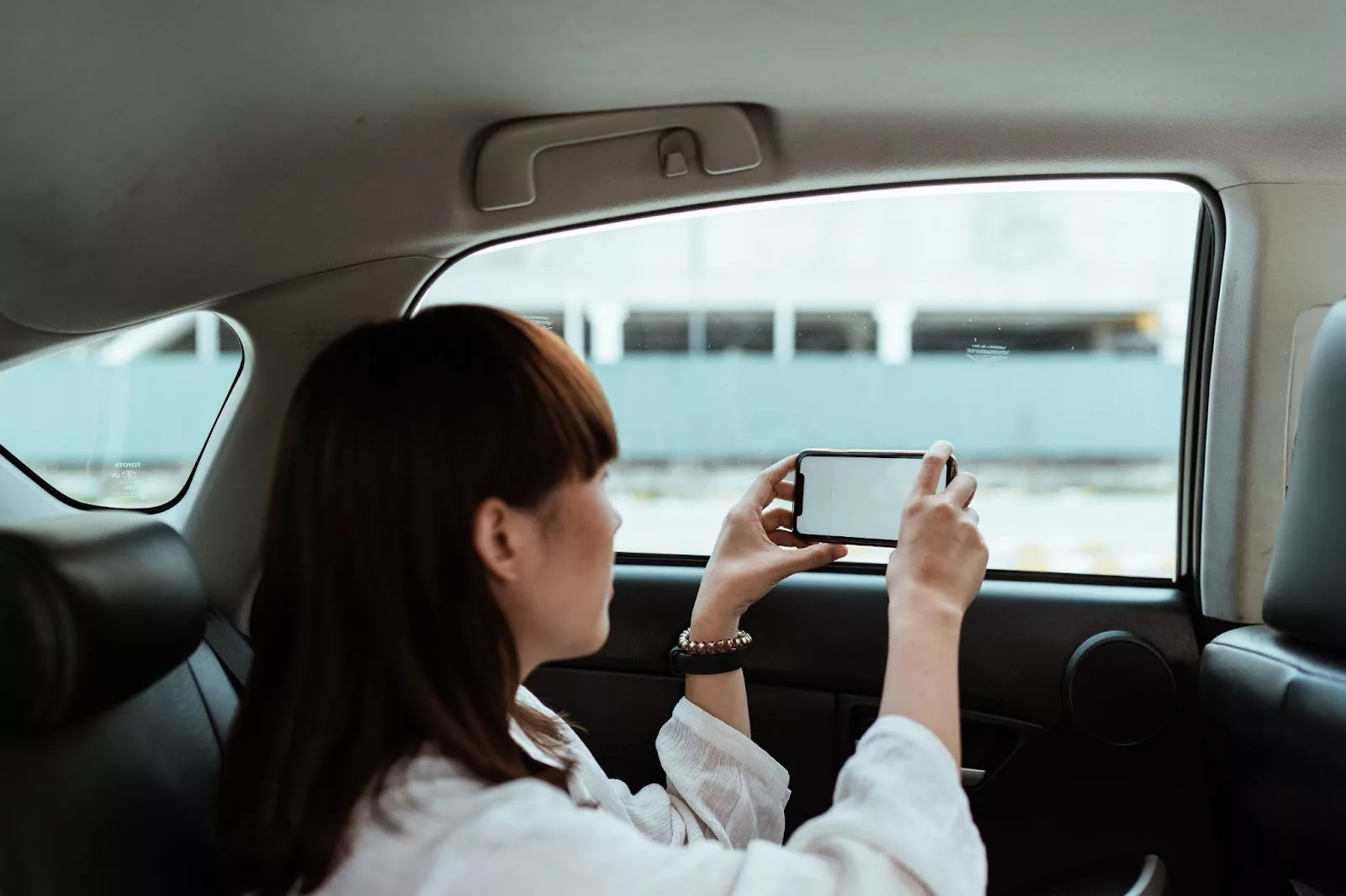 woman taking a photo out of a car window with a phone