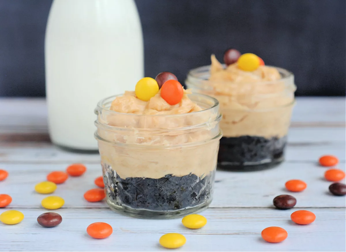 miniature cheesecakes in mini mason jars topped with Reeses Pieces