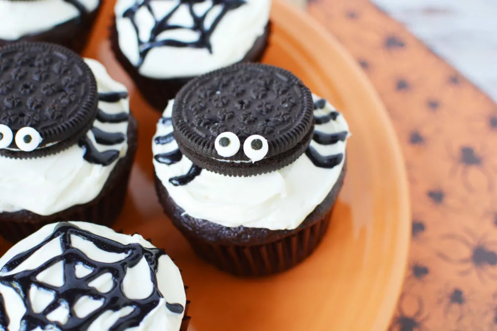 chocolate cupcakes topped with vanilla frosting and oreos decorated to look like spiders