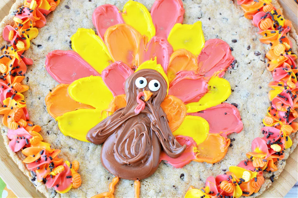 a giant chocolate chip cookie decorated with a turkey and festive fall colors