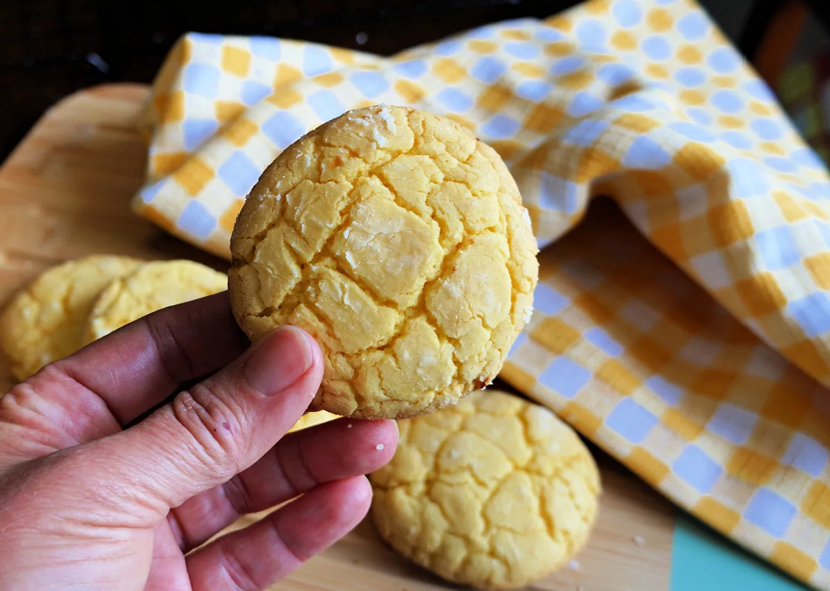 A hand holding a cookie made of lemon cake mix.