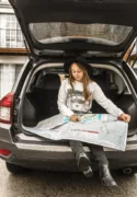 woman sitting in the back of her SUV with a road map