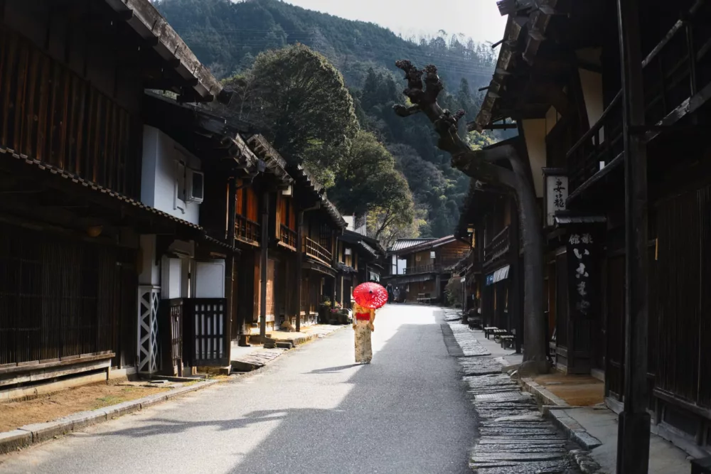 geisha walking down a street in Japan in a red Kimono