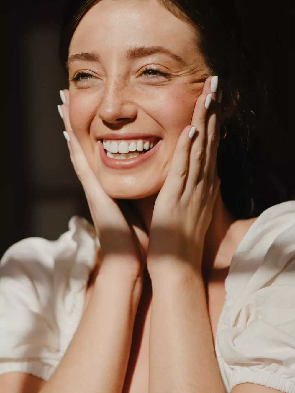 woman smiling and holding her face in her hands