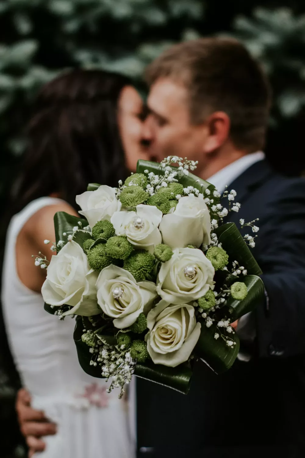 married couple holding a bouquet while kissing