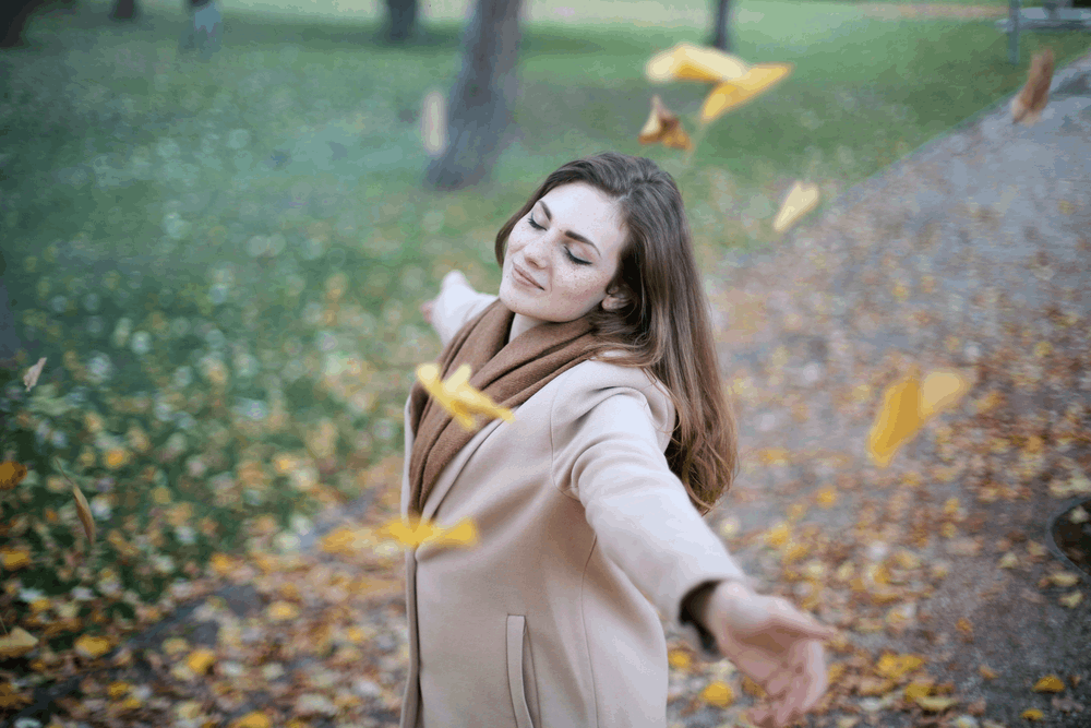 woman enjoying the blowing leaves
