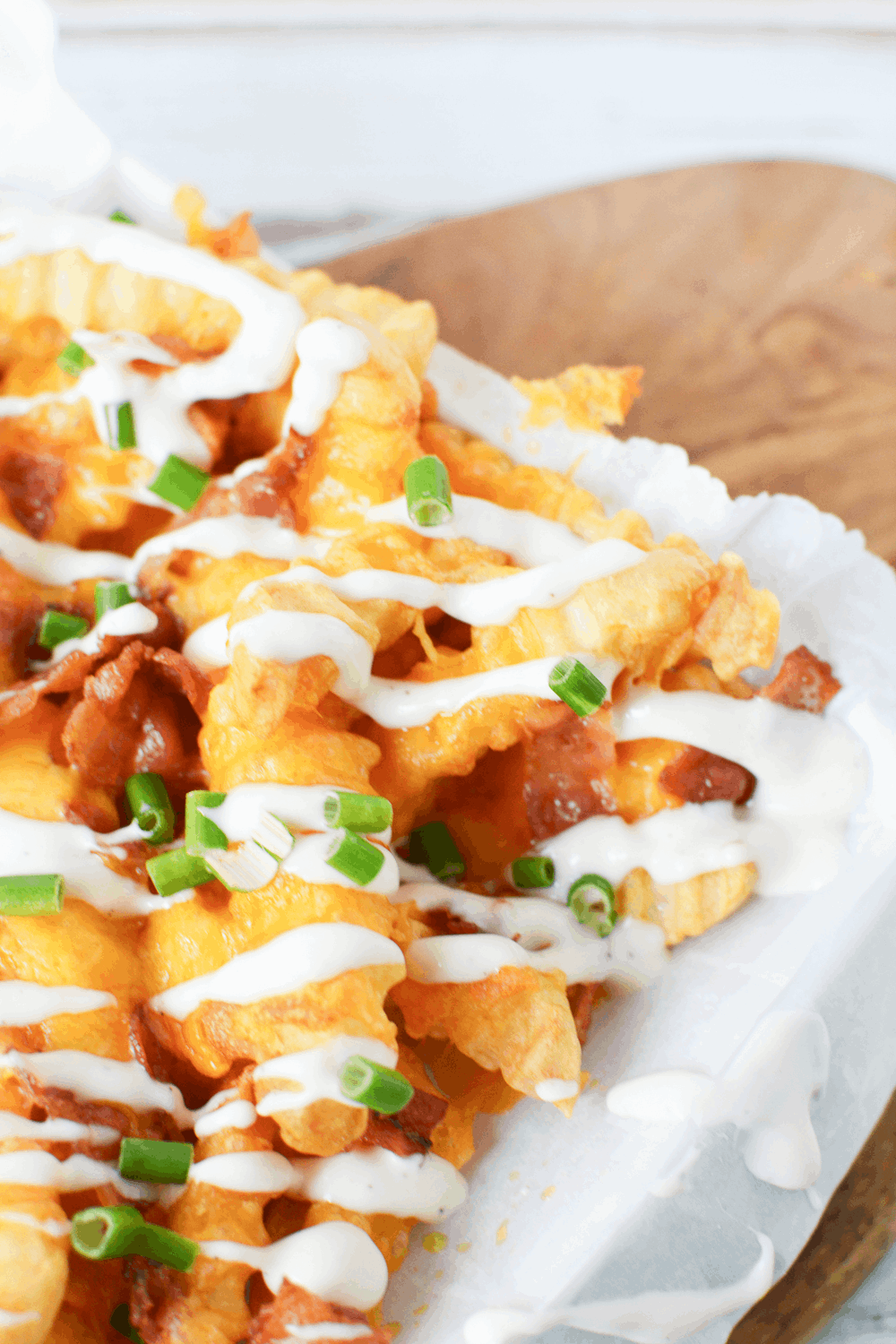 Air Fryer Frozen French Fries covered in bacon, melted cheddar cheese and ranch dressing