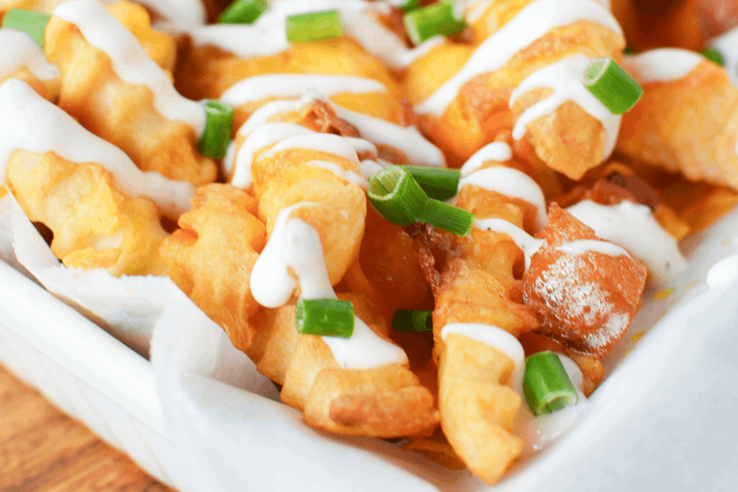 Air Fryer Frozen French Fries covered in bacon, melted cheddar cheese and ranch dressing