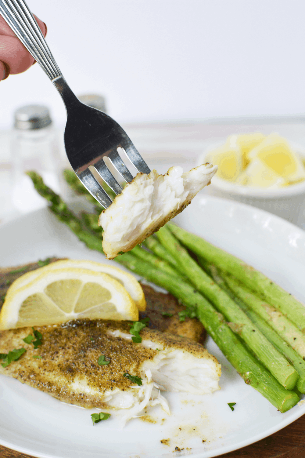 Closeup shot of air fryer frozen fish fillets with asparagus on a fork