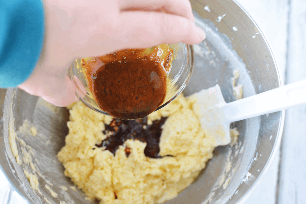 bowl filled with cookie batter and pouring a cup of instant coffee into the batter