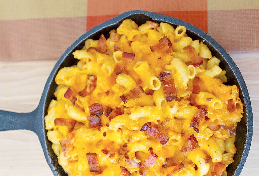 overhead shot of cast iron pan filled with macaroni and cheese and pieces of bacon
