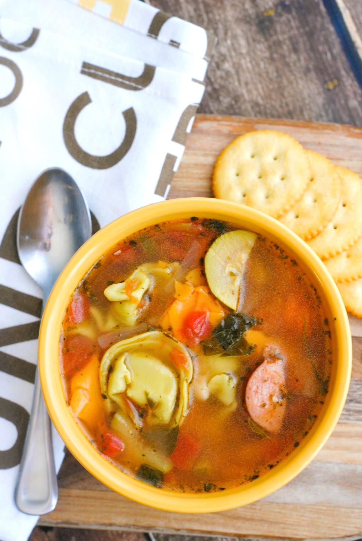 Tortellini and Sausage Soup with crackers on the side of the bowl