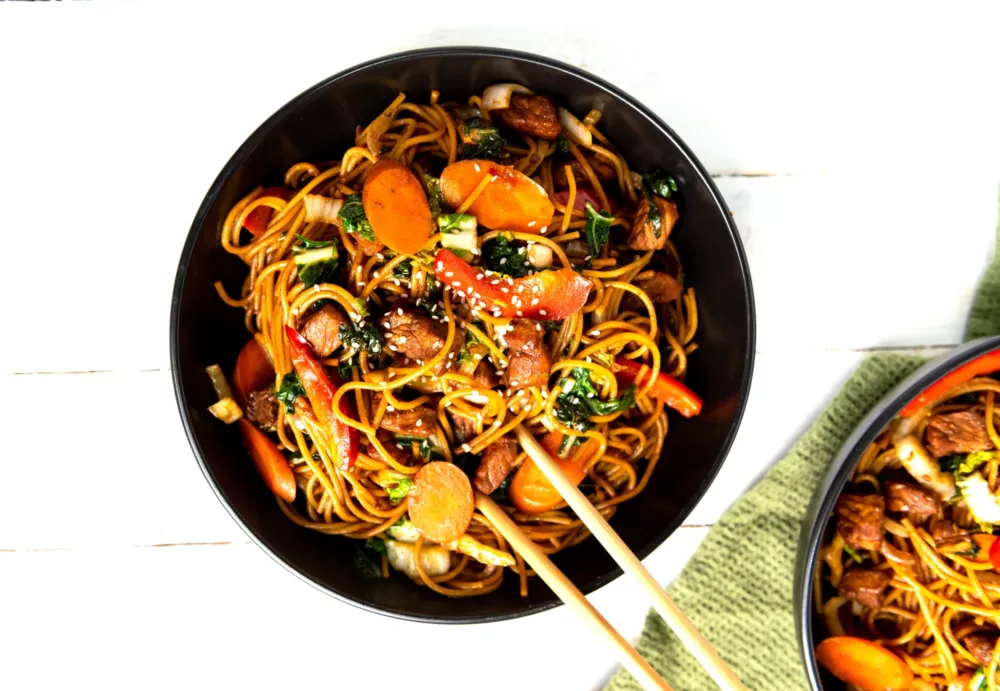 Lo Mein on a plate with beef, carrots and peppers.