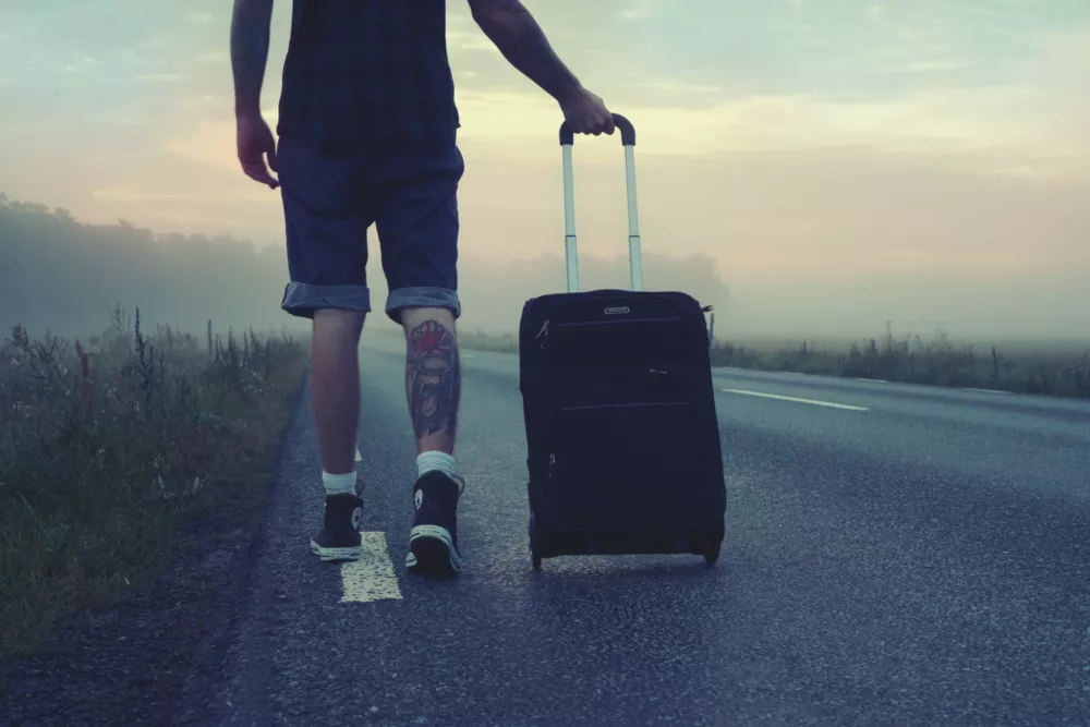 man in sneakers rolling a suitcase