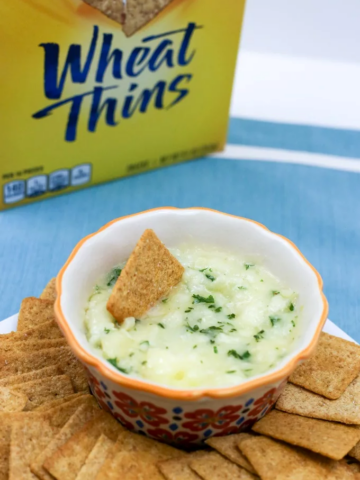 Baked Garlic Brie in a bowl with wheat thin crackers