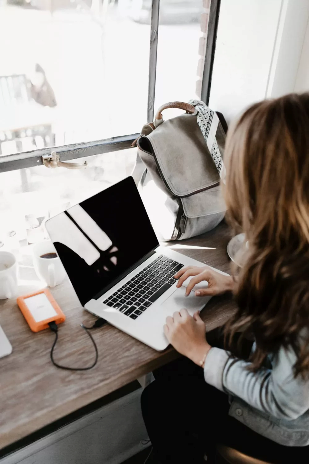 woman working on her laptop in front of a window