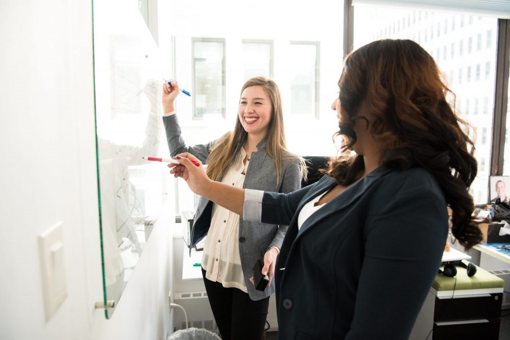 women standing in front of a white board