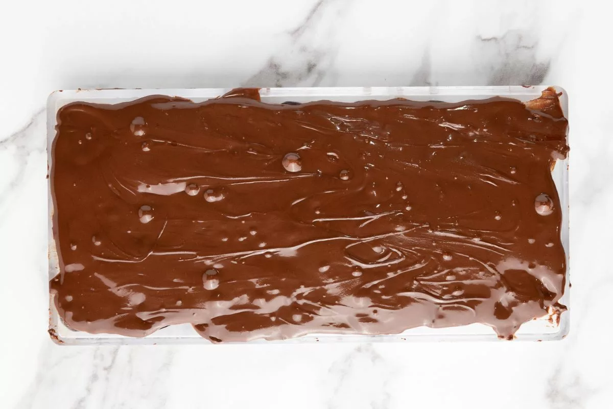 Overhead shot of bonbon mold covered in melted chocolate. 