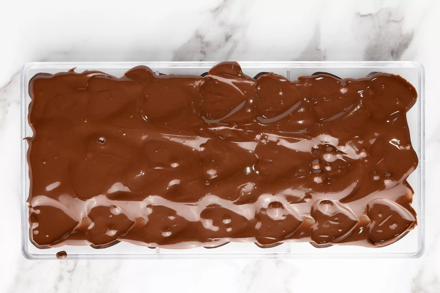 Overhead shot of bonbon mold coated in melted chocolate. 