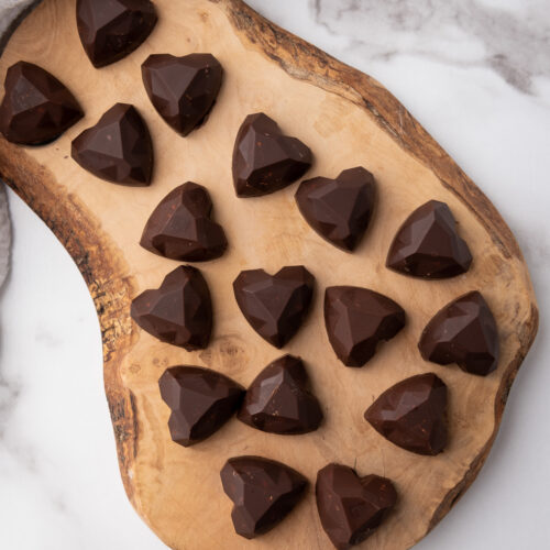 Overhread shot of heart-shaped Nutella bites on wooden board