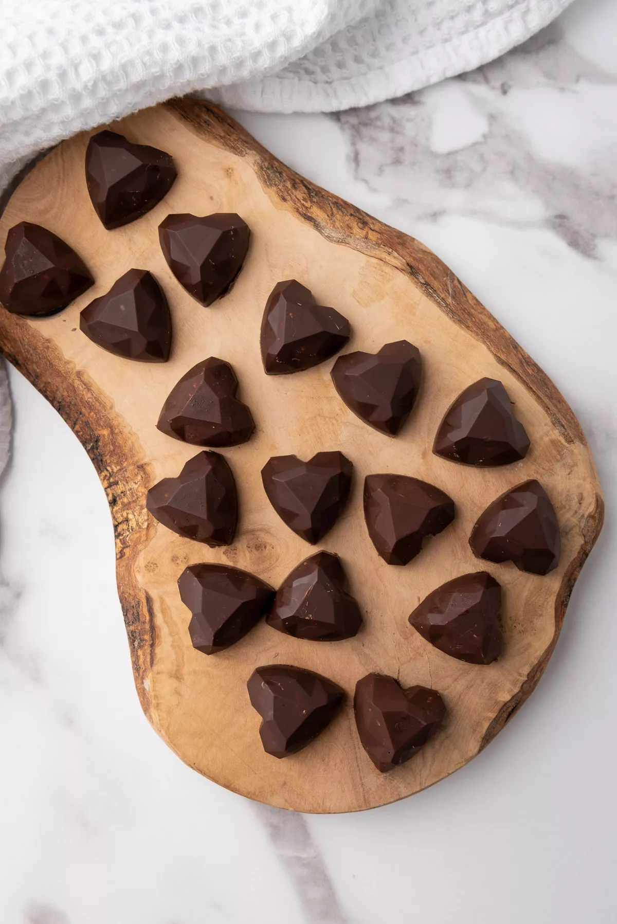 Overhread shot of heart-shaped Nutella bites on wooden board