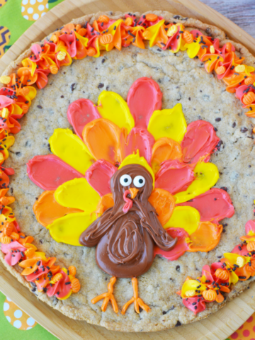 chocolate chip cookie decorated with yellow, orange and red frosting with a turkey
