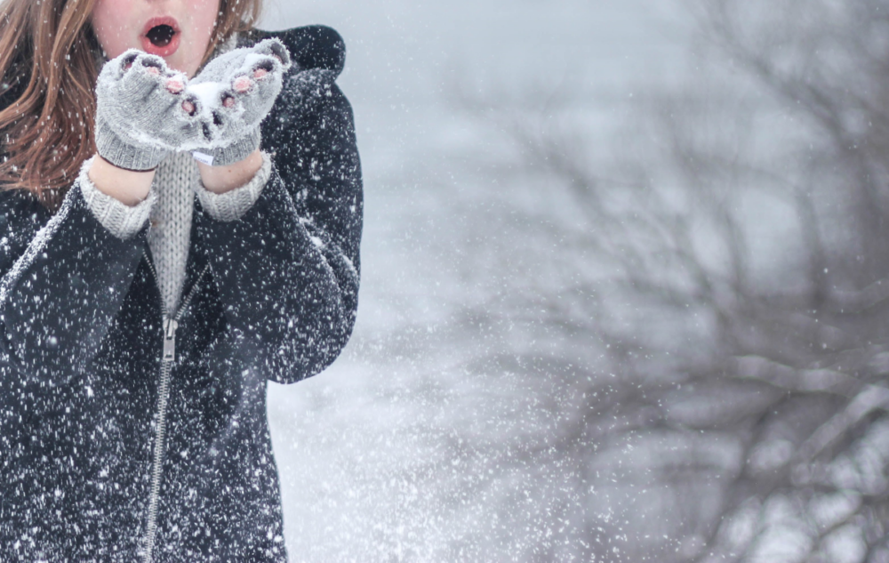 woman blowing snows from her mittens