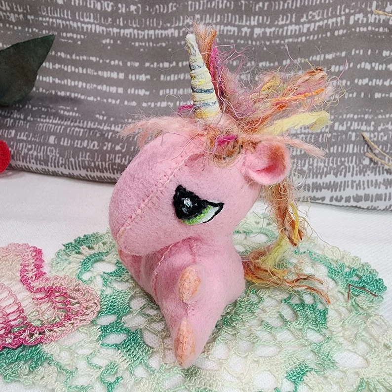 Pink felt baby unicorn with large eyes and fabric mane. 