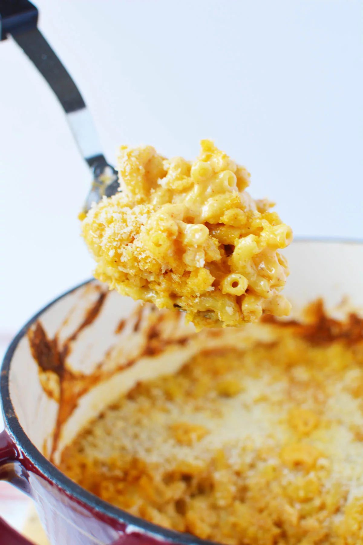 A serving spoon serving homemade mac and cheese 
