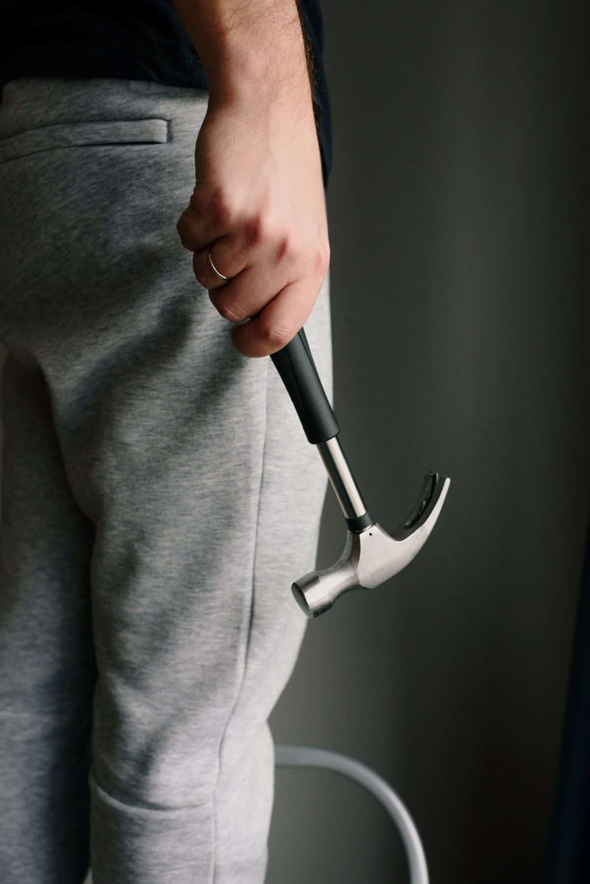 person holding a hammer in grey sweatpants