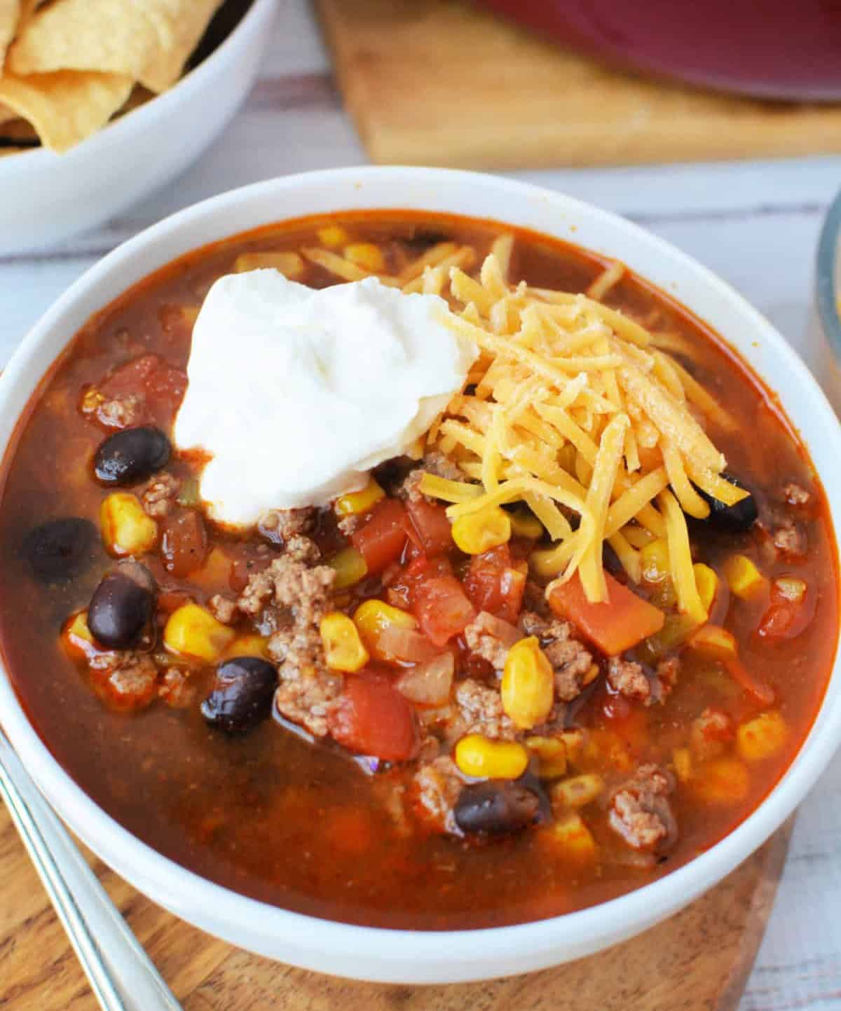 Beef Enchilada Soup topped with shredded cheddar cheese and a dallop of sour cream