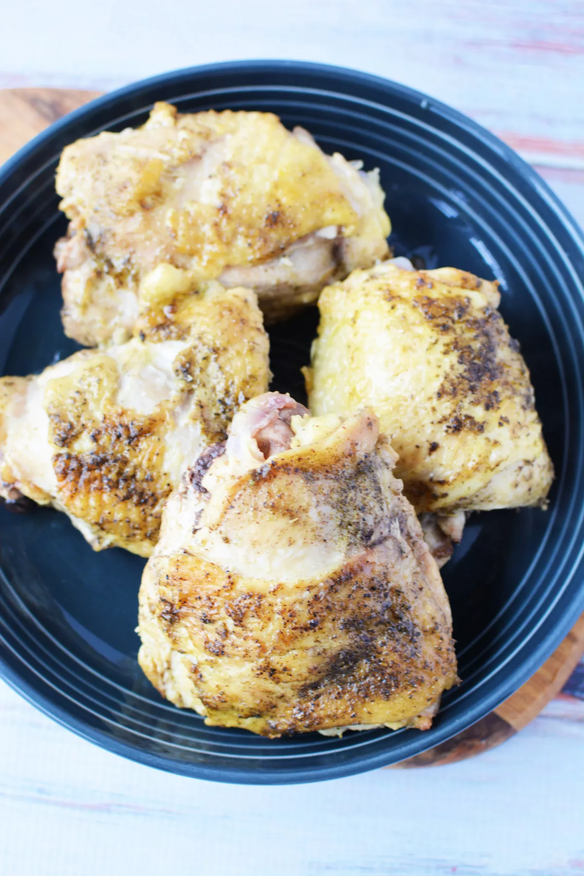 Overhread shot of Dutch oven chicken thighs with crispy skin on plate. 
