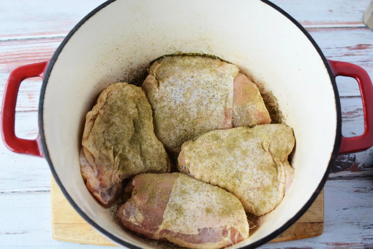Overhead shot of seasoned chicken thighs in Dutch oven.