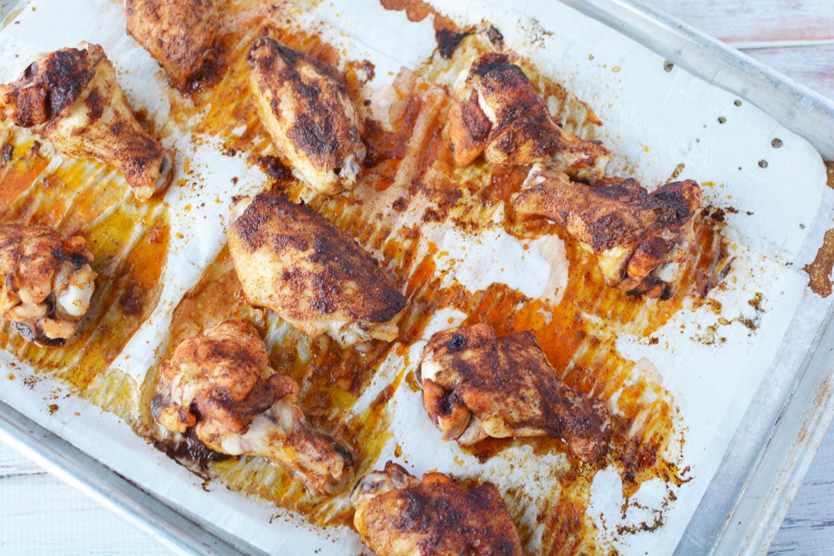 Overhead shot of cooked seasoned chicken wings on baking sheet lined with parchment paper. 