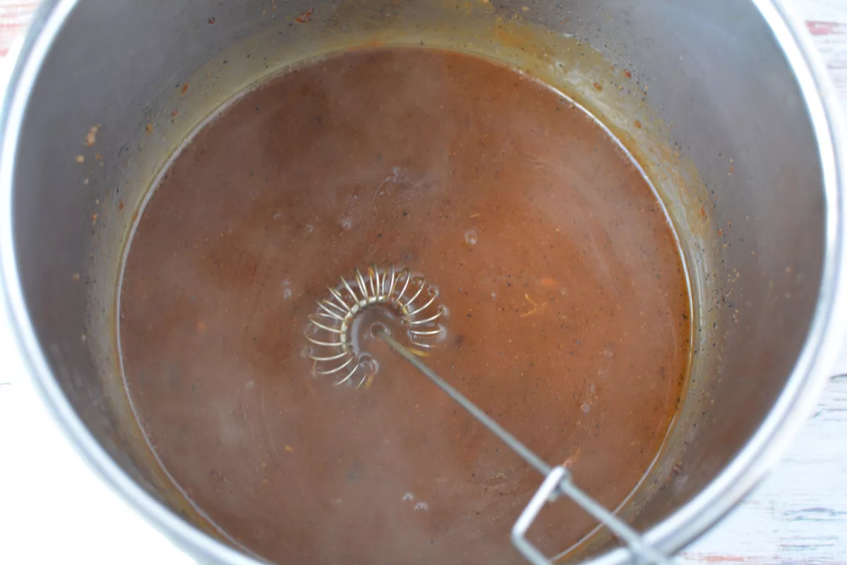 Overhead shot of whisk standing up in Instant Pot with gravy inside.