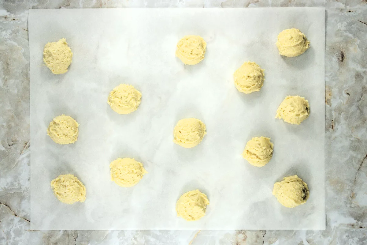 cookie dough balls on a parchment paper lined baking sheet