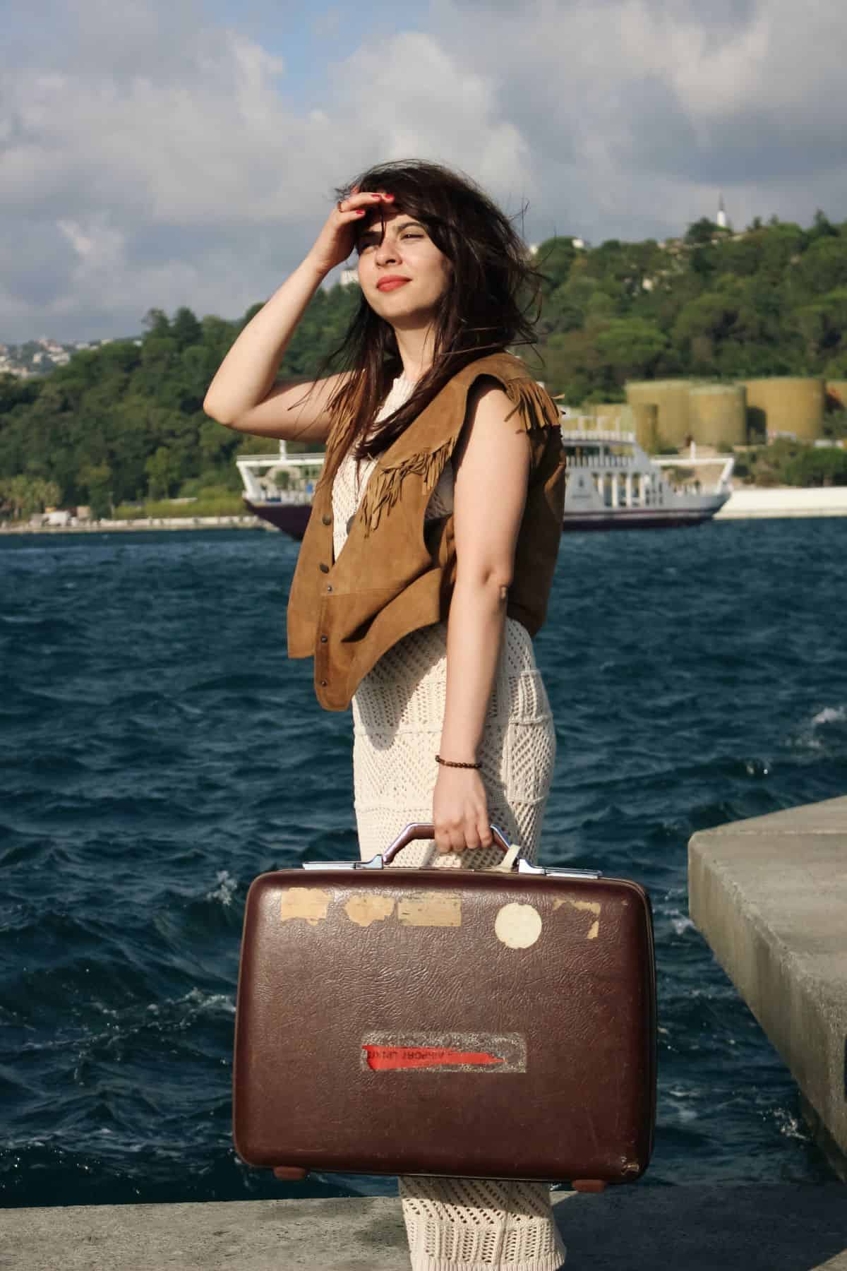 woman standing on a dock with a suitcase in her hand