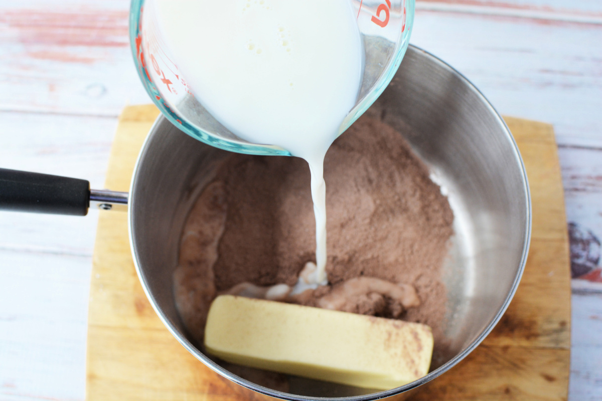 Milk being poured into pan with pudding mix and butter. 