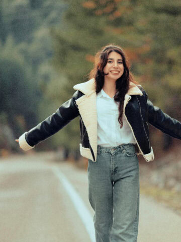 woman in a leather jacket with shearling lining walking on a road