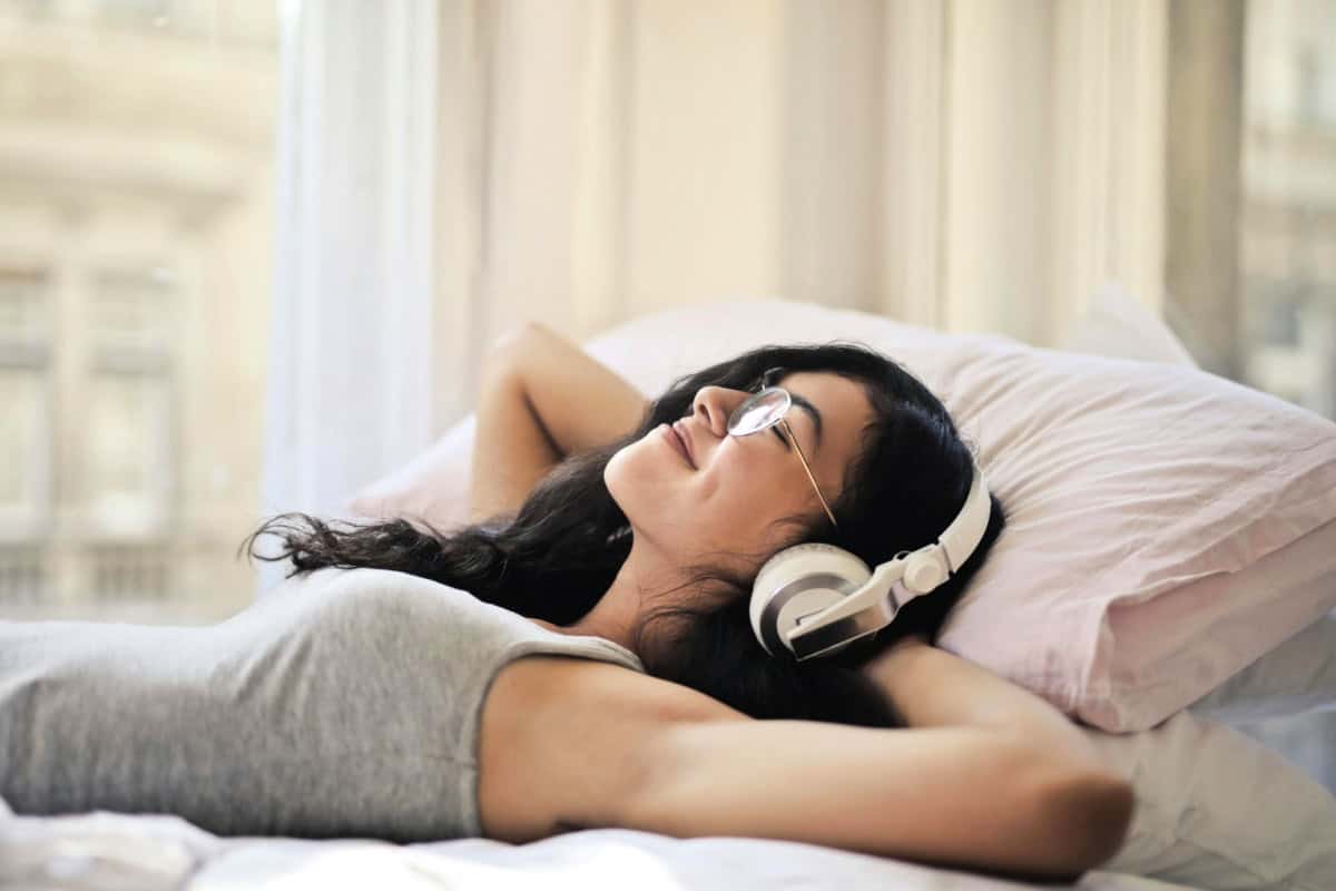 woman with headphones on in bed