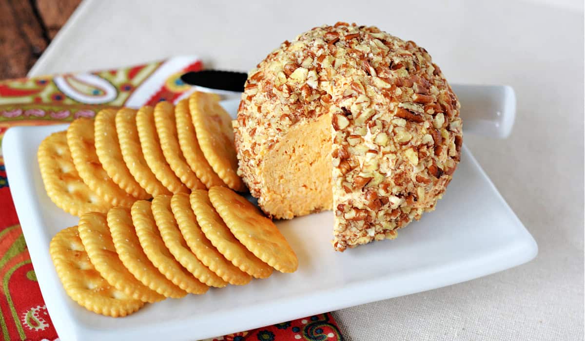 Classic Cheese Ball Appetizer topped with pecans with crackers on a plate